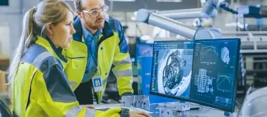 Two engineers designing a mechanical device on a computer.